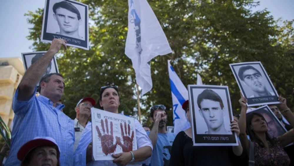 Click photo to download. Caption: On July 28, relatives of Israelis killed in terror attacks hold signs as they demonstrate outside of the Prime Minister's Office ahead of the Israeli cabinet vote on the proposal to free 104 terrorist prisoners for the restarting of Israel-Palestinian conflict talks. The prisoner release proposal passed in a 13-7 vote. Credit: Yonatan Sindel/Flash90.