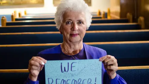 A woman holds a “We Remember” sign as part of the the World Jewish Congress's social media campaign. Credit: Facebook.