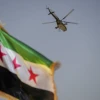 A military helicopter flies above a Syrian flag during the Syria Summer Family Festival in Damascus, Syria, on Aug. 9, 2026. Photo by Omar Albam / Middle East Images / AFP via Getty Images.