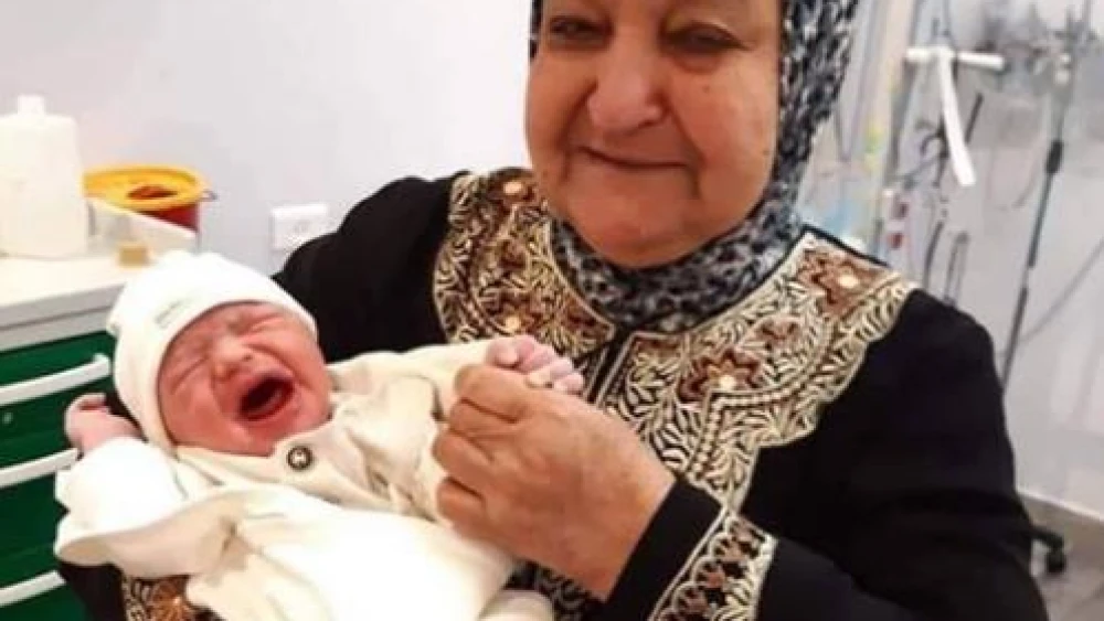 The text accompanying this image, which was posted to the official Fatah Facebook page on June 15, reads: “A child from smuggled sperm. The mother of prisoners and martyrs, Um Nasser Abu Hmeid, holds her grandson Yaman in her arms, the son of prisoner Nasr Abu Hmeid, who is serving five life sentences.” (PMW)