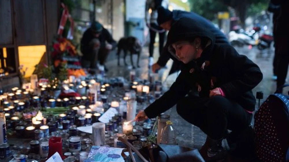 Israelis light memorial candles outside the Simta bar on Dizengoff Street in Tel Aviv on Jan. 3, 2016, two days after two Israeli Jews were killed at that bar in a shooting attack by a suspected Arab terrorist. Credit: Ben Kelmer/Flash90.