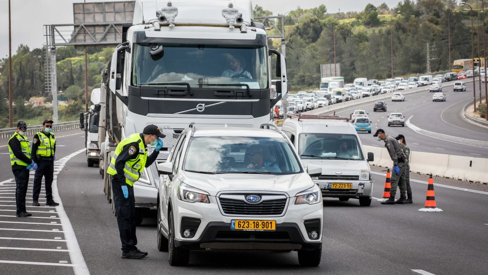 An Israeli police officer at a temporary coronavirus “checkpoint“ on Highway 1 outside of Jerusalem. Photo by Nati Shohat/Flash90.