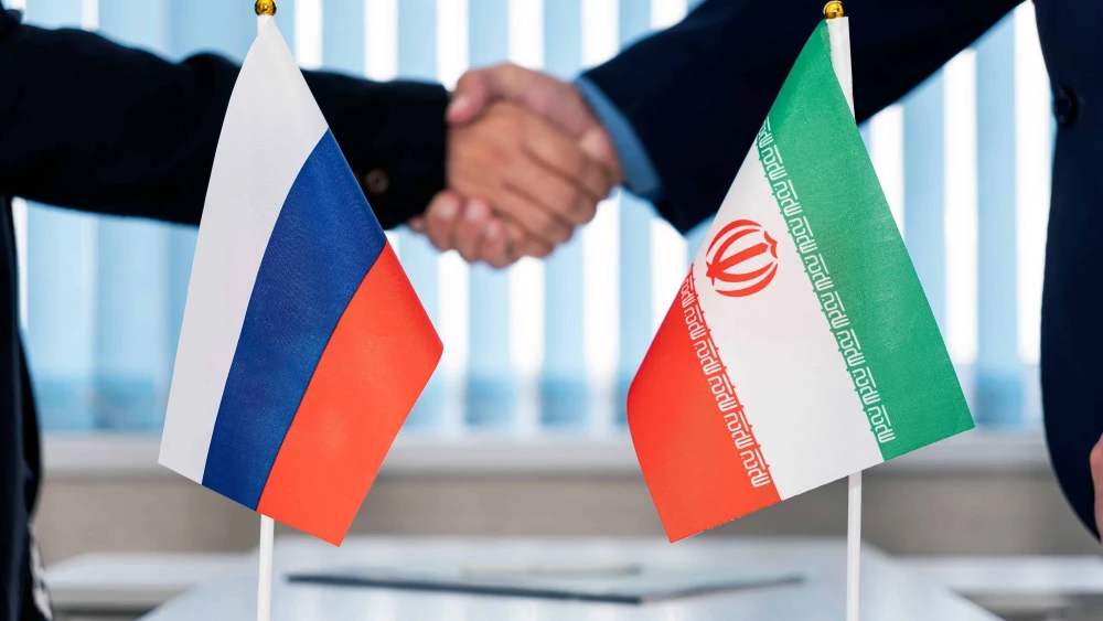 Flags of Russia and Iran on a table in an international negotiation room. Credit: Melnikov Dmitriy/Shutterstock.