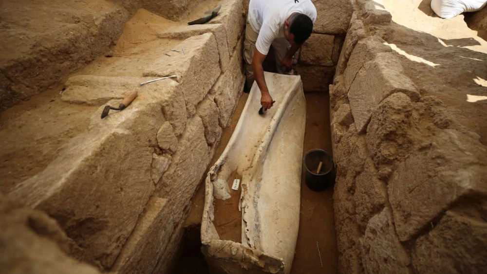 A Palestinian archaeologist works on a 2,000 year-old lead sarcophagus discovered during the excavation of a Roman cemetery in the northern Gaza Strip, July 16, 2023. Photo by Majdi Fathi/TPS.