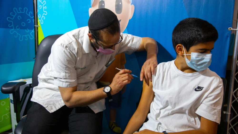 A young Israeli receives a booster shot of the Pfizer/BioNTech COVID-19 vaccine, Sept. 20, 2021. Photo by Olivier Fitoussi/Flash90.