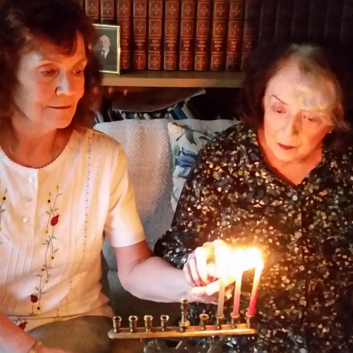 Margery B. Sterns (right), 96, a a longtime resident of San Francisco, lights the menorah with her daughter Sandra. Margery recalls her Russian immigrant parents lighting the menorah as one of her top memories of Hanukkah. Credit: Courtesy.