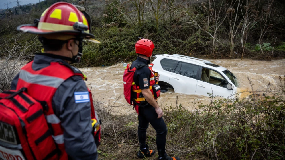 Rescue teams next to a car stranded by flood waters near the entrance to Jerusalem, Jan. 16, 2022. Photo by Yonatan Sindel/Flash90.
