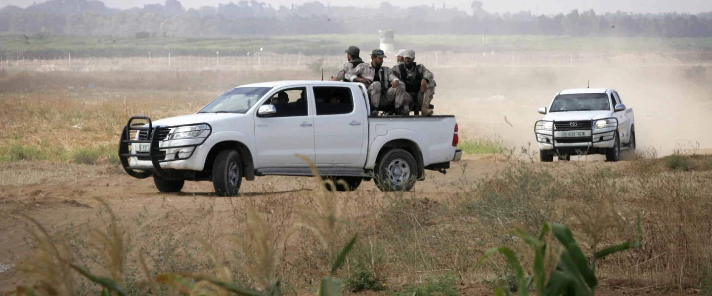 Palestinian terrorists of the Ezzedine al-Qassam Brigades, Hamas' armed wing, sit in the back of a pick-up truck watching Israeli bulldozers working along a barbed wire fence that separates Khan Yunis in the southern Gaza Strip and the Israeli border, on June 10, 2015. Photo by Abed Rahim Khatib/Flash 90.