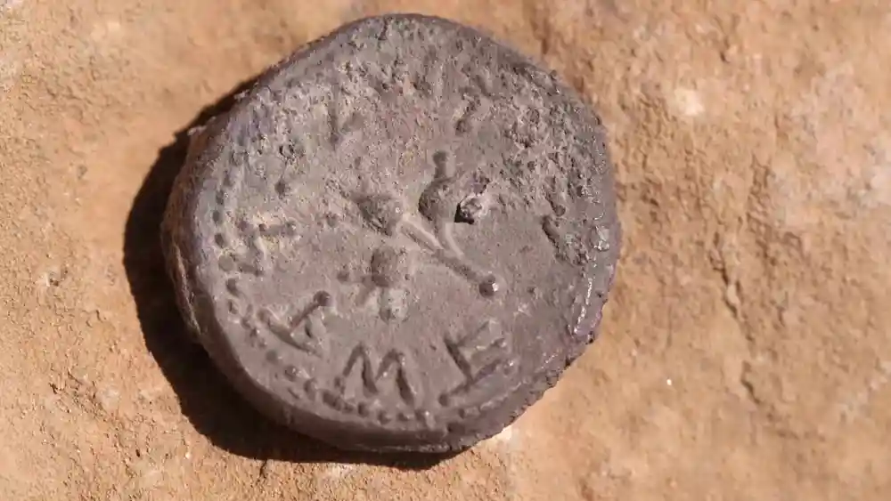 A 2,000-year-old coin discovered at the entrance to a cave in the Judean Desert, bearing an inscription reading "Holy Jerusalem" in ancient script. Credit: Emil Aladjem/IAA.