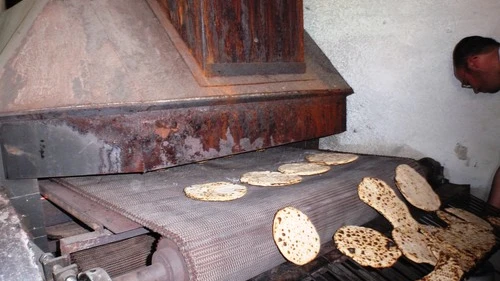 Handmade matzah comes out of the oven. Credit: Ariel Palmon via Wikimedia Commons.