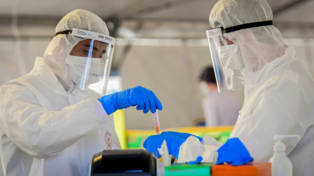 Magen David Adom medical team members handle a coronavirus test sample at a drive-through testing site in Tel Aviv on March 22, 2020. Photo by Flash90.