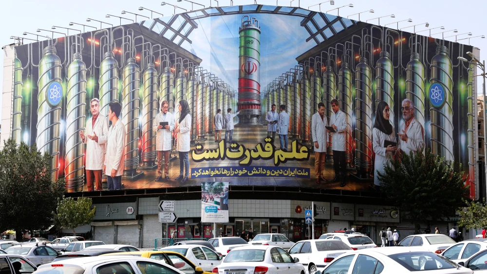 Iranians drive next to a billboard displaying pictures of nuclear scientists, centrifuges and a sentence reading in Farsi: "Science is the power," at Enqelab Square in Tehran on Aug. 29, 2025. Photo by AFP via Getty Images.