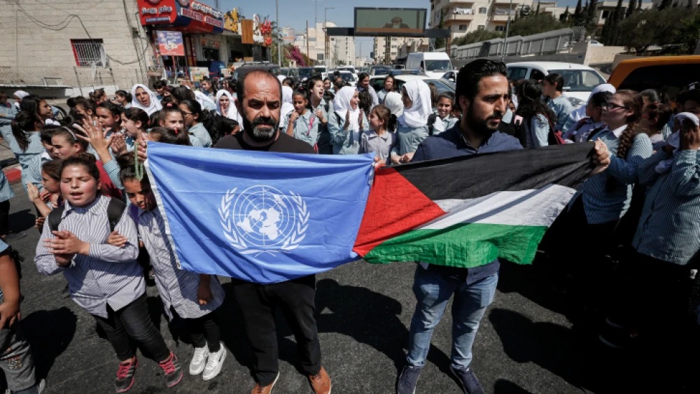 Palestinian protesters wave flags during a protest in Bethlehem against the U.S. decision to cut U.N. aid to Palestinians if the funds don’t stop going to support terrorists and their families, on Sept. 26, 2018. Photo by Wisam Hashlamoun/Flash90.